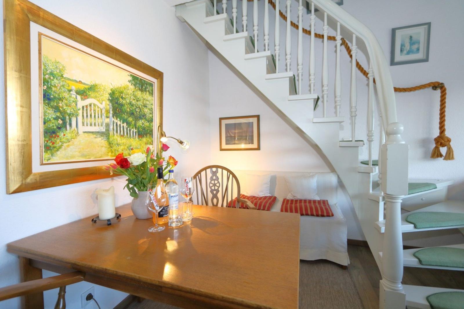 Dining area with table, chair, and wall art under staircase.