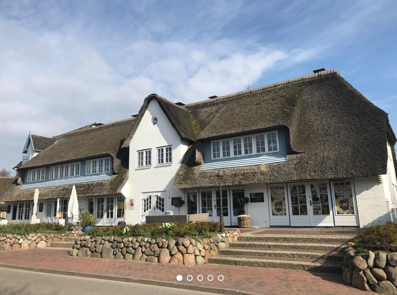 House with thatched roof, white walls and windows, entrance stairs and garden