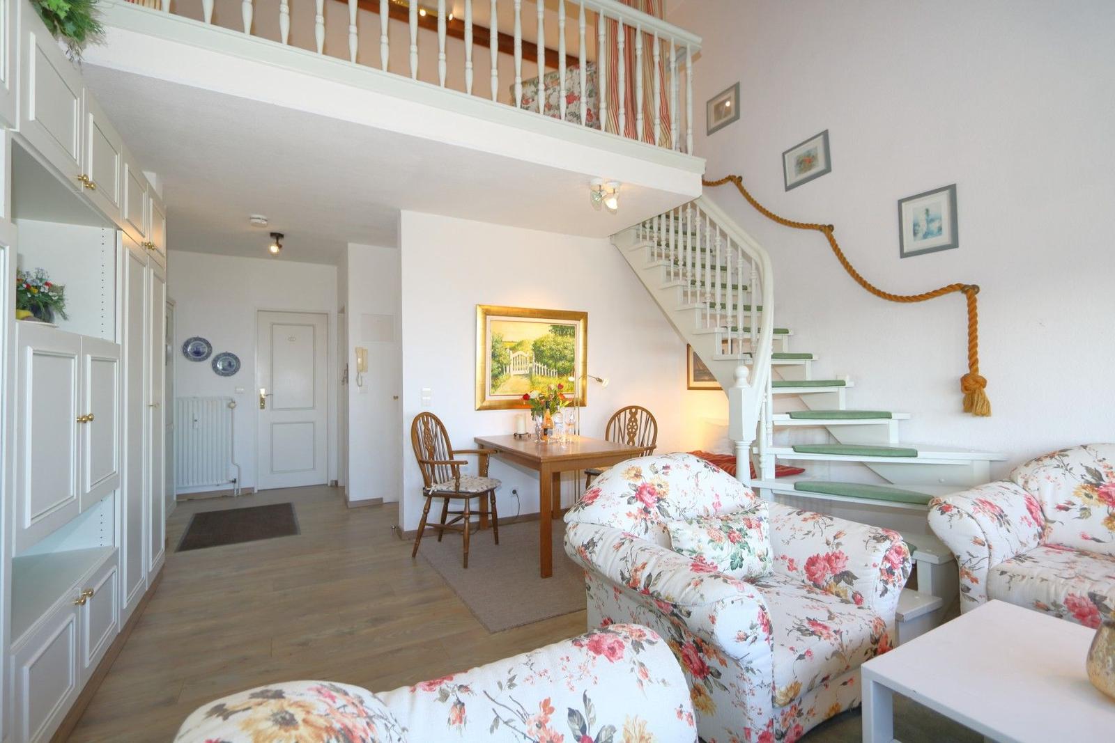 Living area with staircase, seating group, and dining area under sloped ceiling