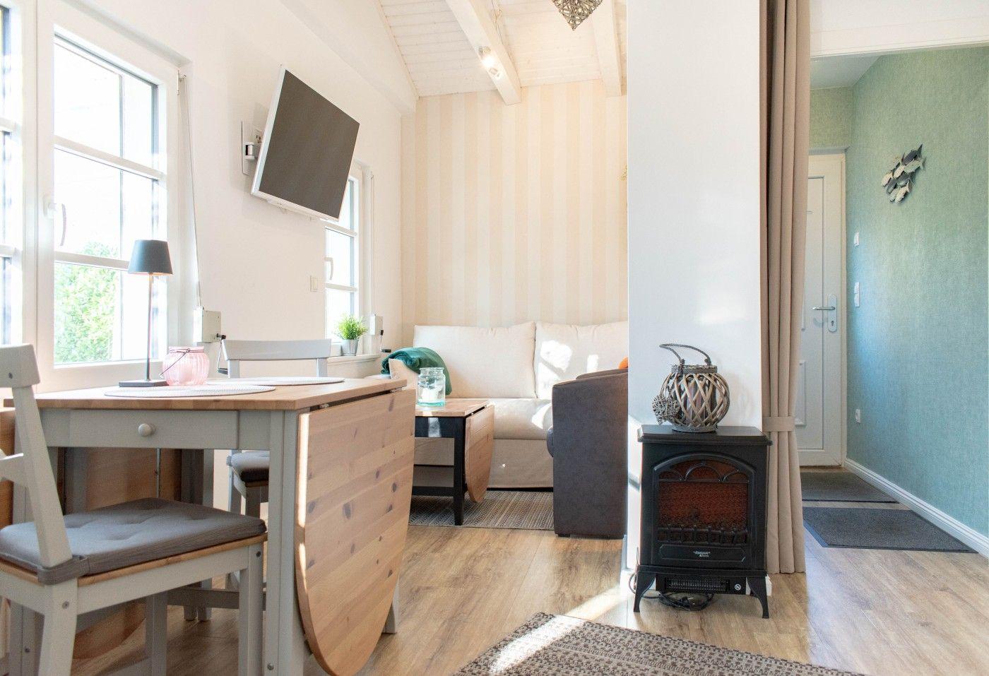 Wohn- und Essbereich mit Sofa, Tisch, TV und Kaminofen.