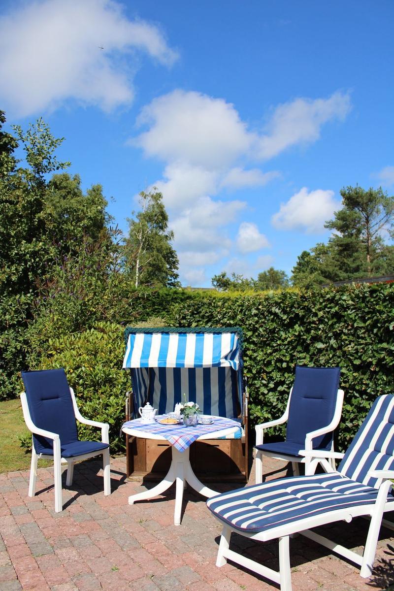 Terrace with blue and white lounge chairs and table under blue sky.