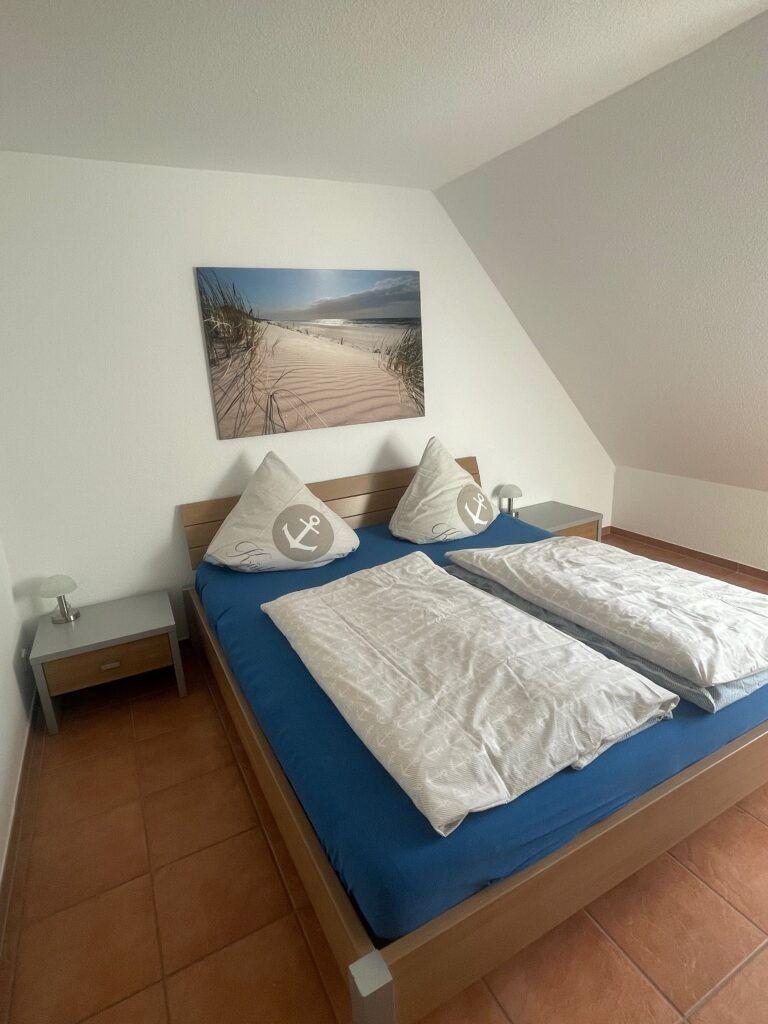 Schlafzimmer mit Doppelbett, Wandbild und zwei Nachttischen.