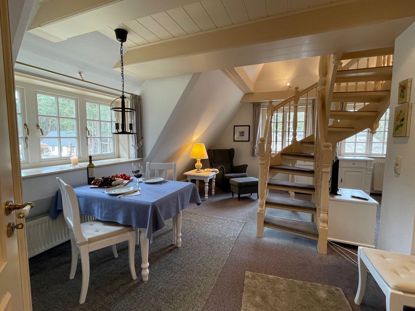 Essbereich mit Tisch, Stühlen und Fenster. Treppe führt zur oberen Etage.