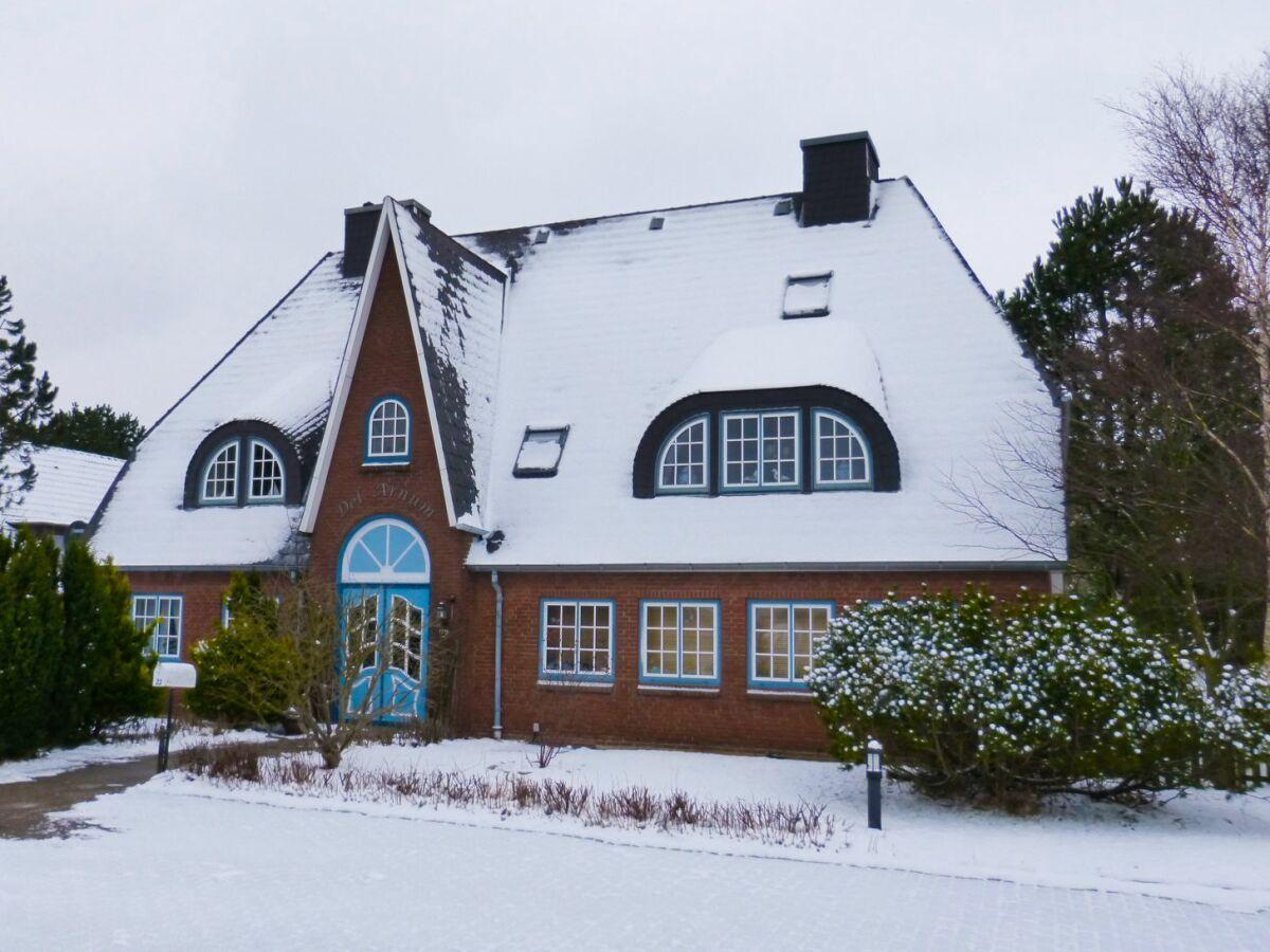 House with snow-covered roof and blue window frames.