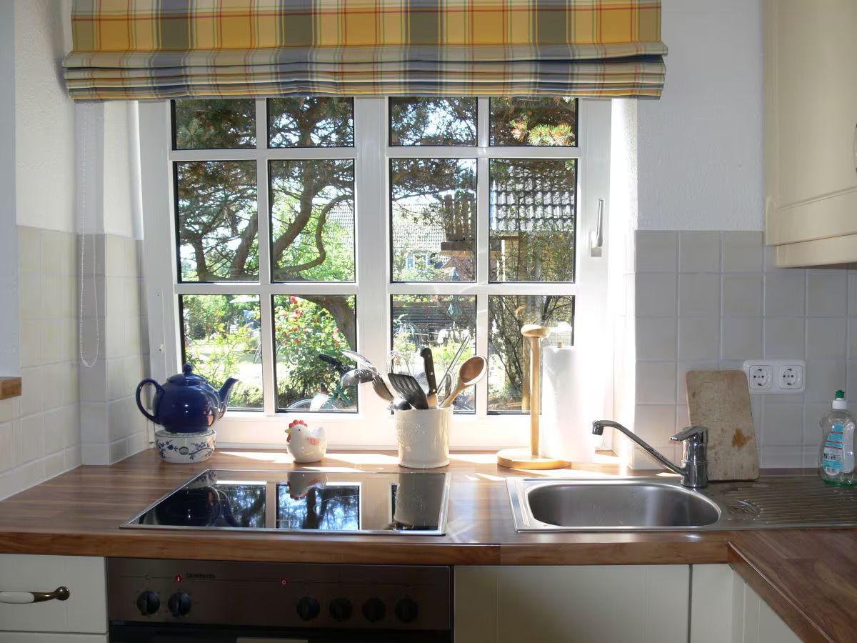 Kitchen with wooden countertop, window, and stove. Trees are visible outside.