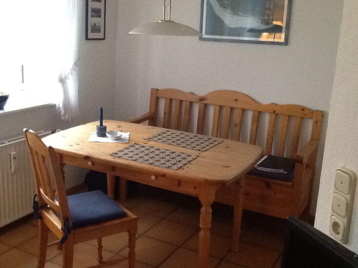 Wooden table with bench and chair, placemats, and wall art in dining room.