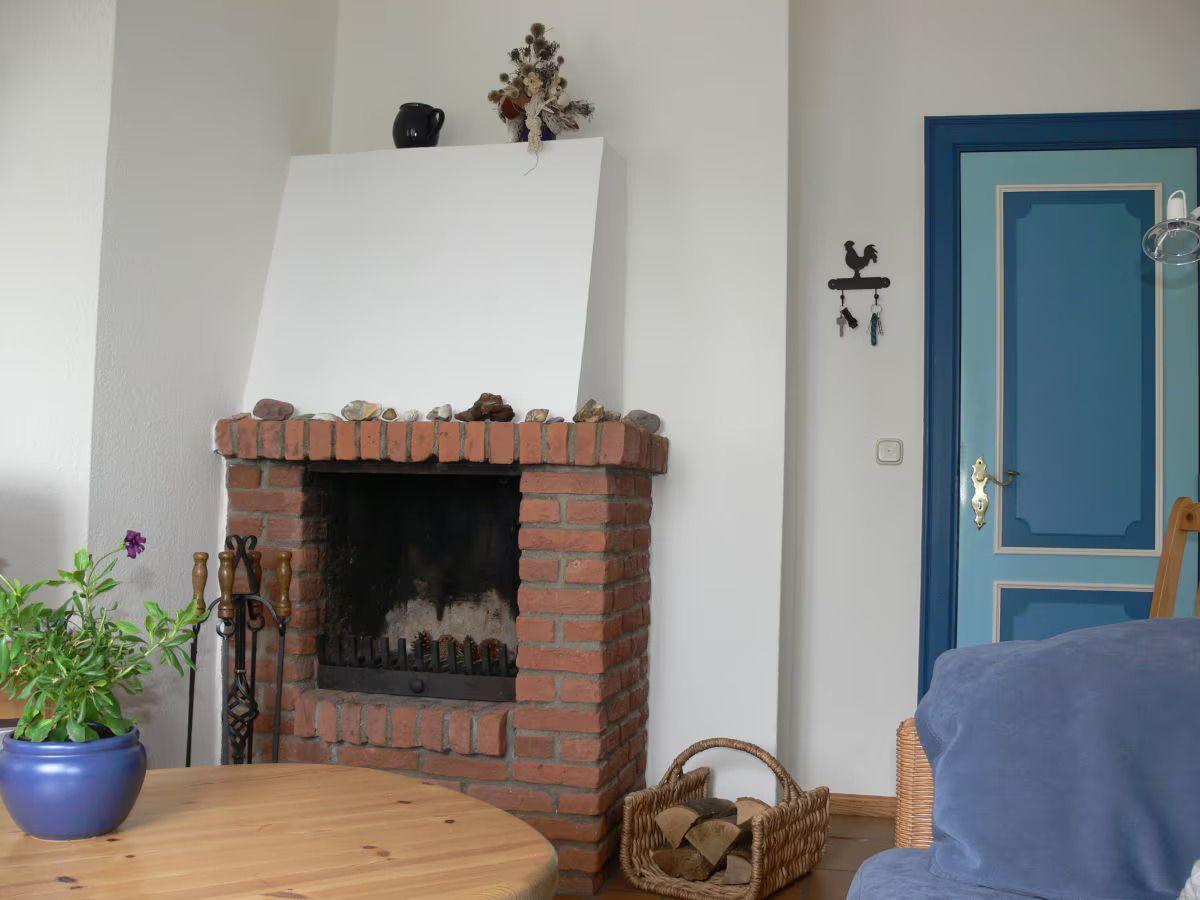 A fireplace with stones, a blue door, and a basket with wood.