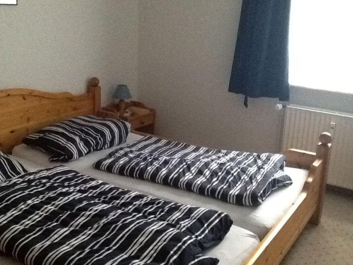 A bedroom with a wooden bed, striped bedding, and a nightstand with a lamp.