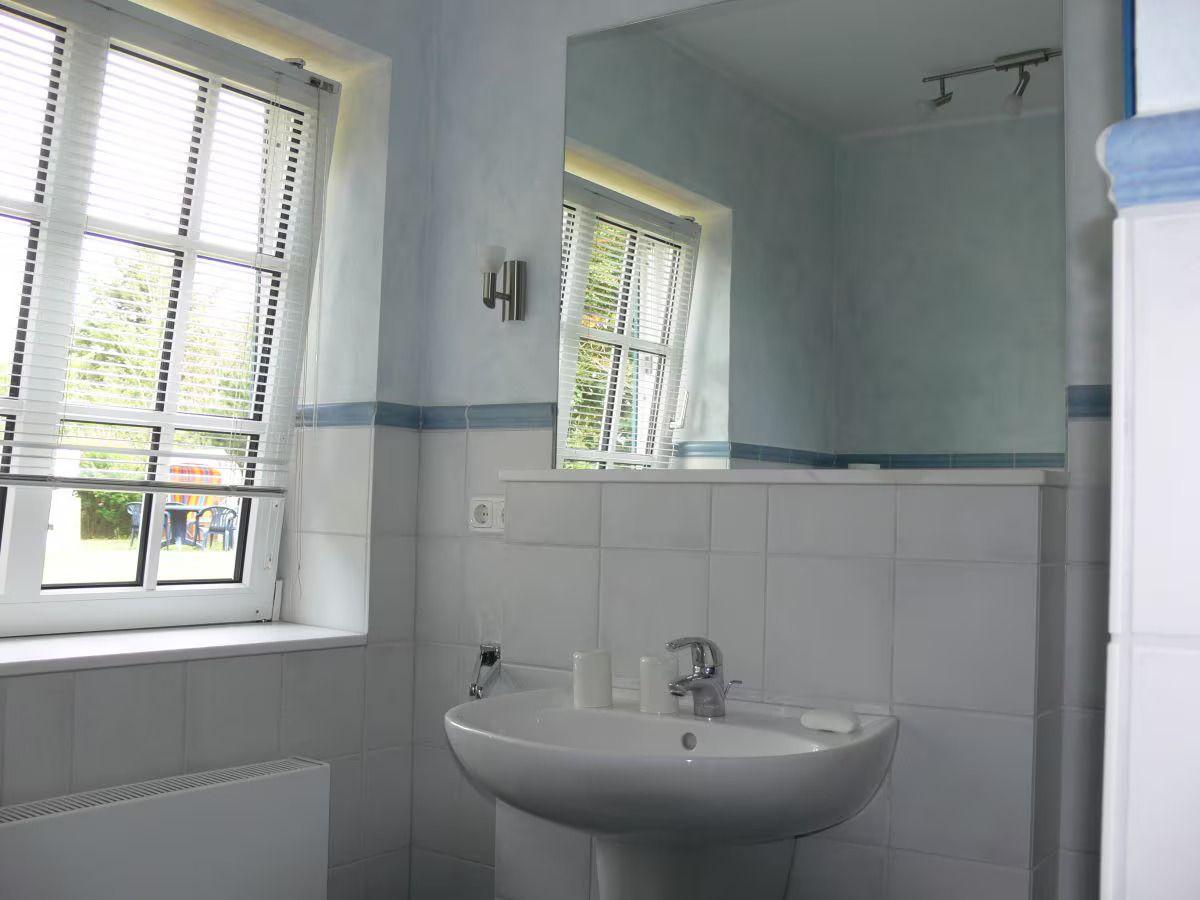 Bathroom with sink, mirror, and window with blinds.