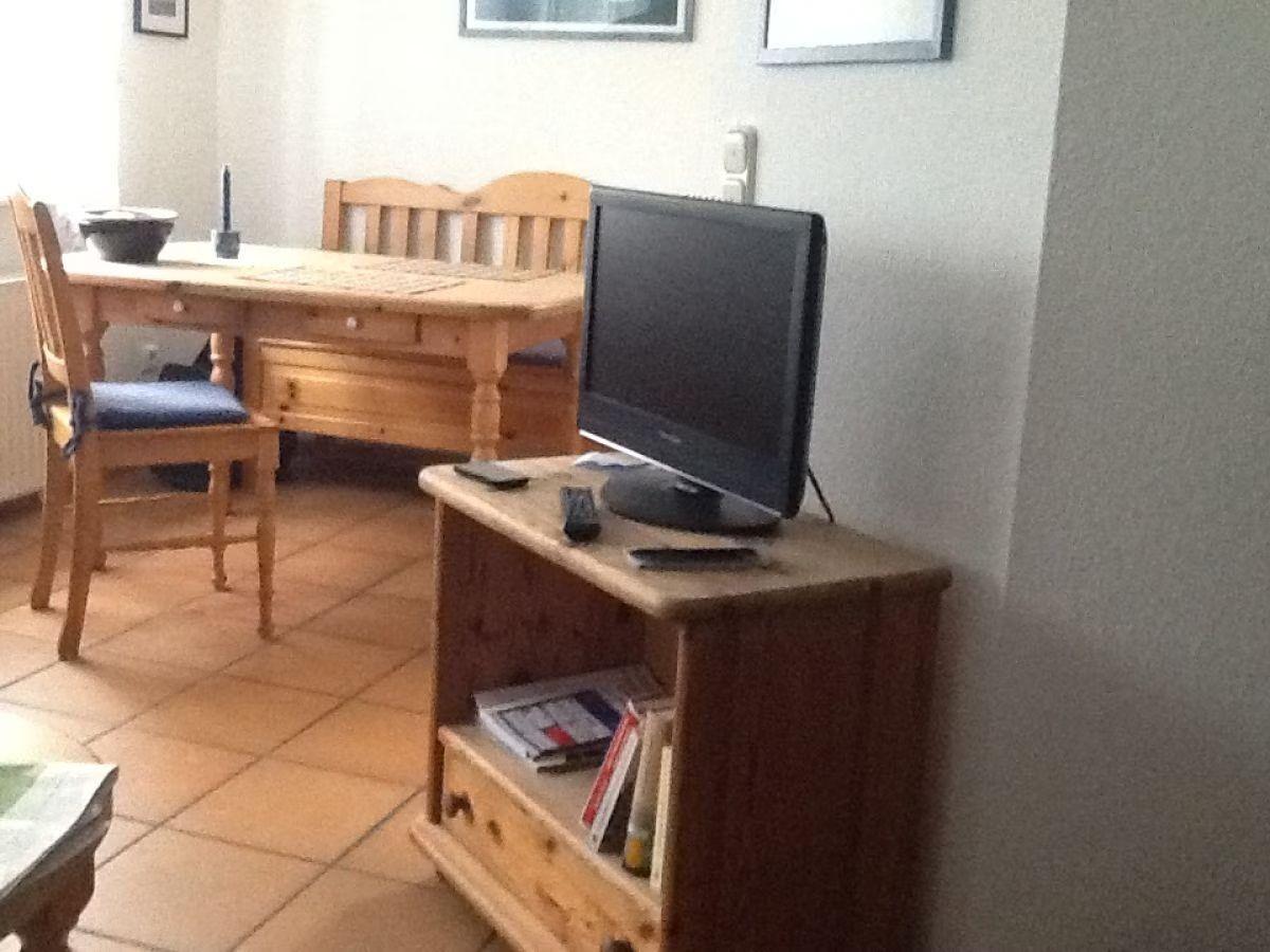 Dining area with wooden table, chairs, and TV on a sideboard.