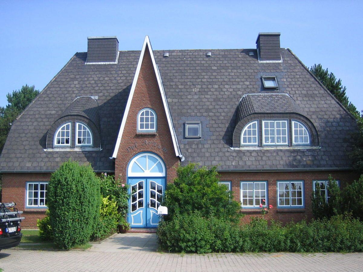 A two-story house with red brick and blue door. Roof with slate and windows.