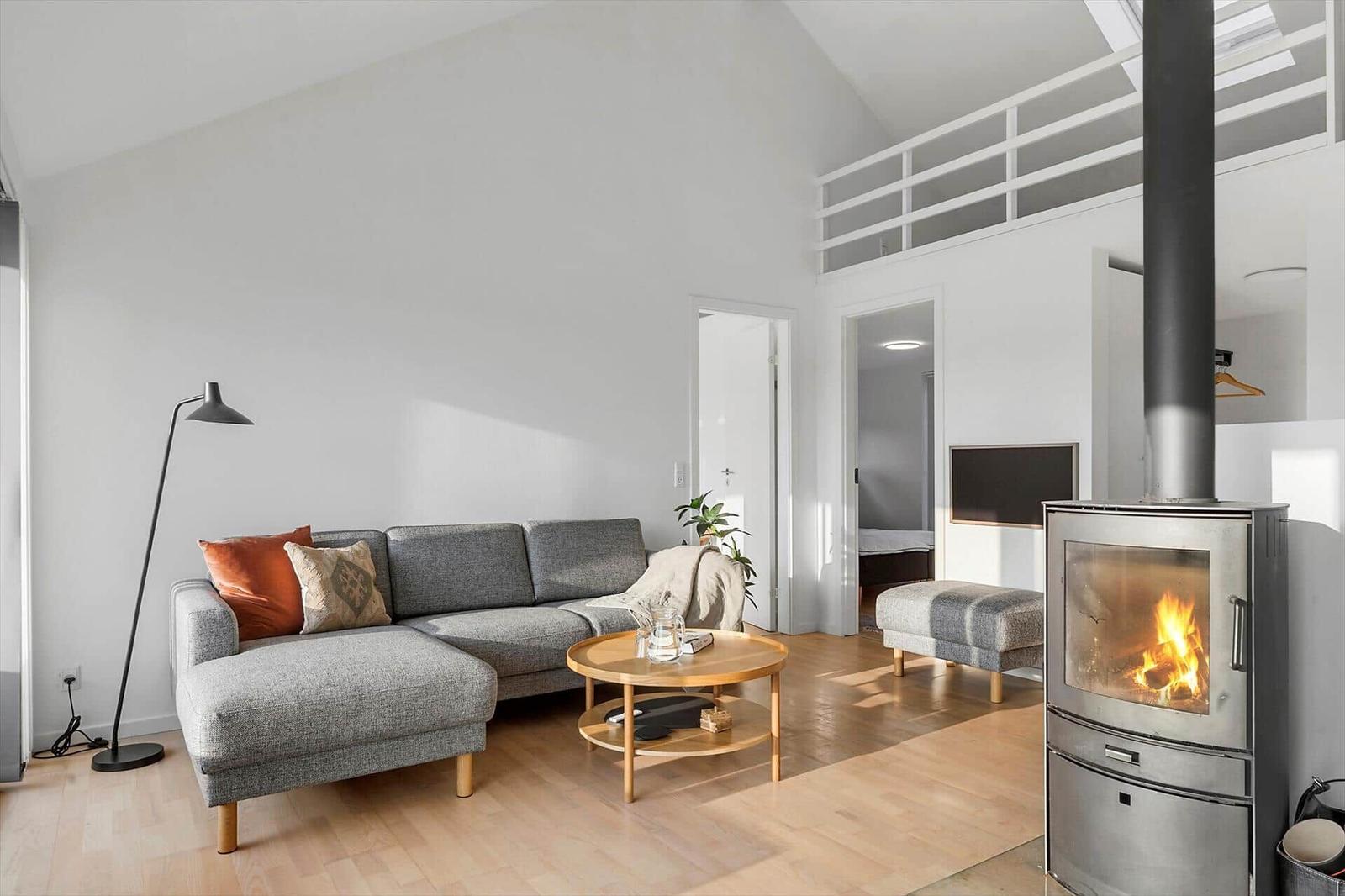 Living room with sofa, fireplace, and wooden floor. Upper level with balcony.