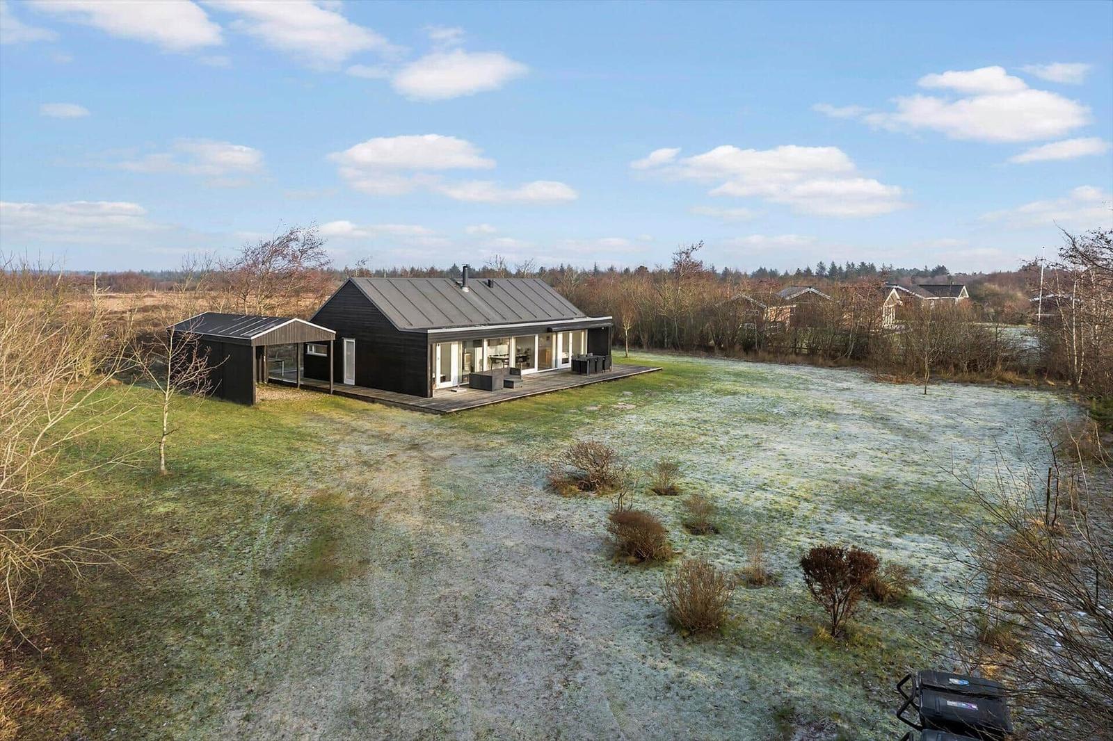Modern villa with large garden and terrace under blue sky.