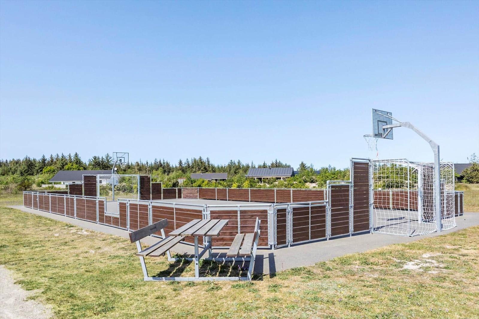 Outdoor play area with basketball hoop, soccer goal, and picnic table.