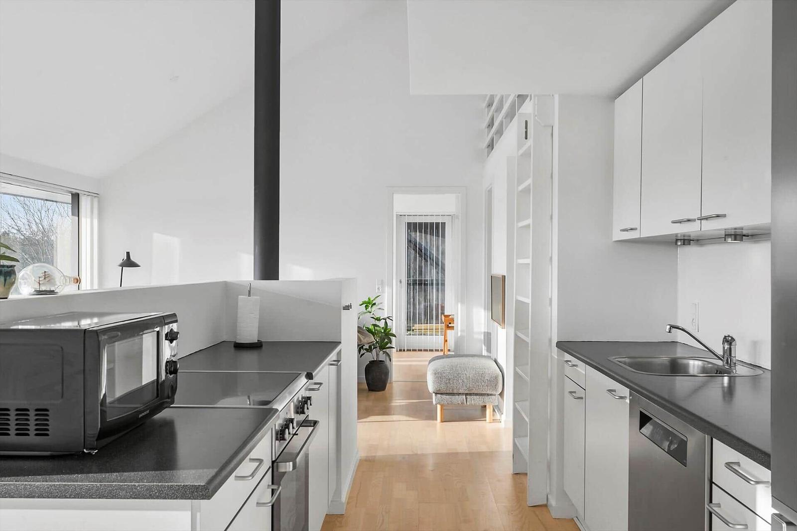 Kitchen with white cabinets, dark countertops, and integrated dishwasher area.