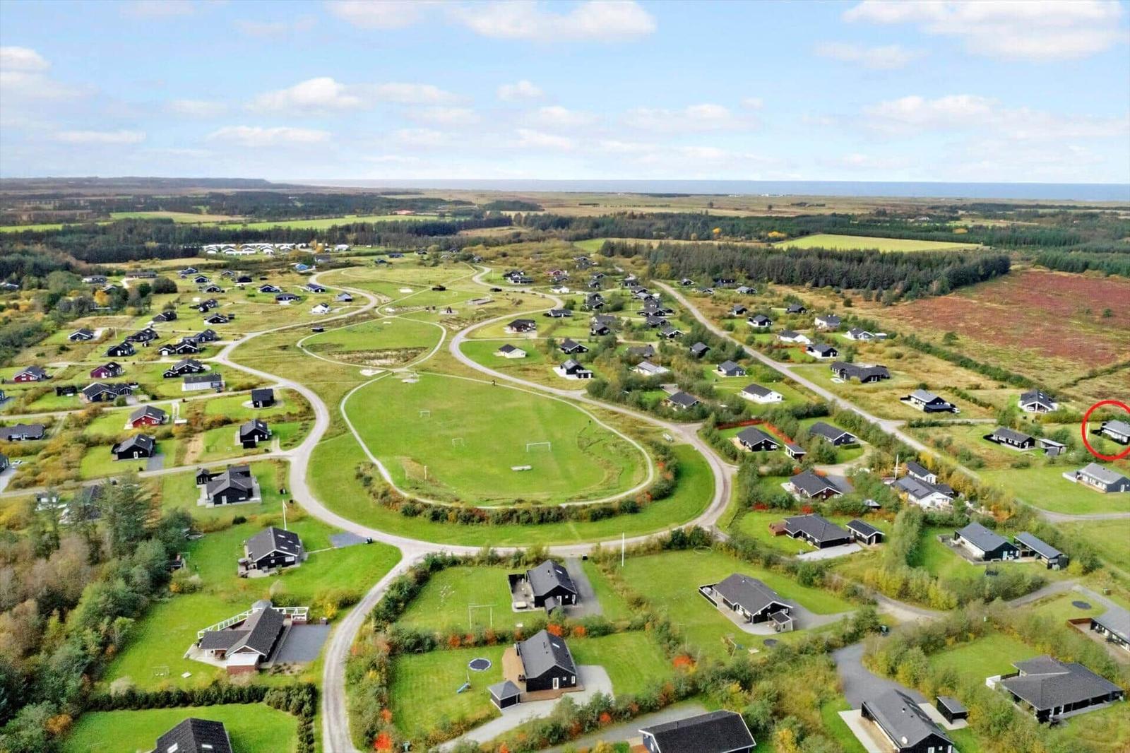 Aerial view of a holiday resort with many houses, green lawns, and a soccer field.