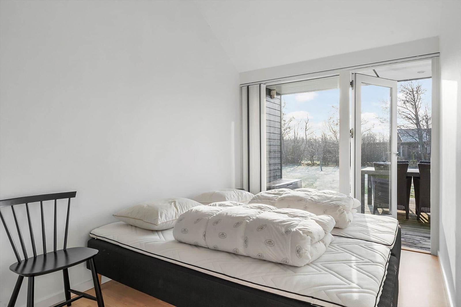 Bedroom with mattress, pillows, and sliding door to balcony.