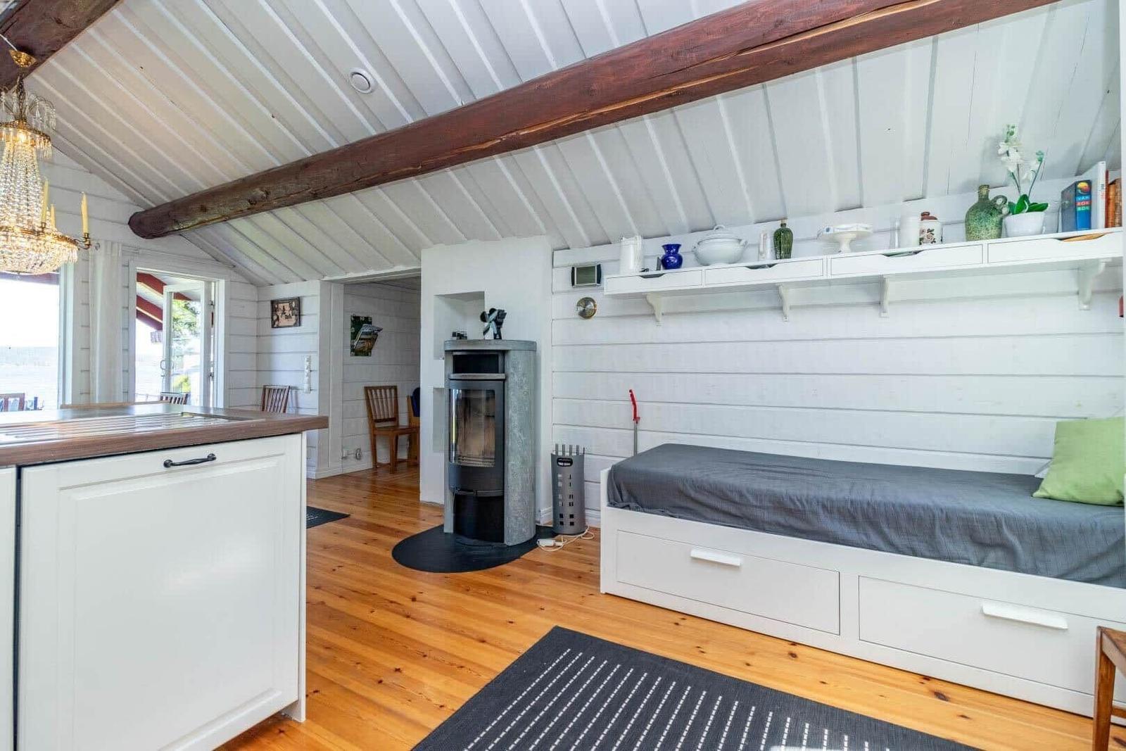 Schlafbereich mit Bett, Kamin und Küchenzeile unter Dachschrägen.