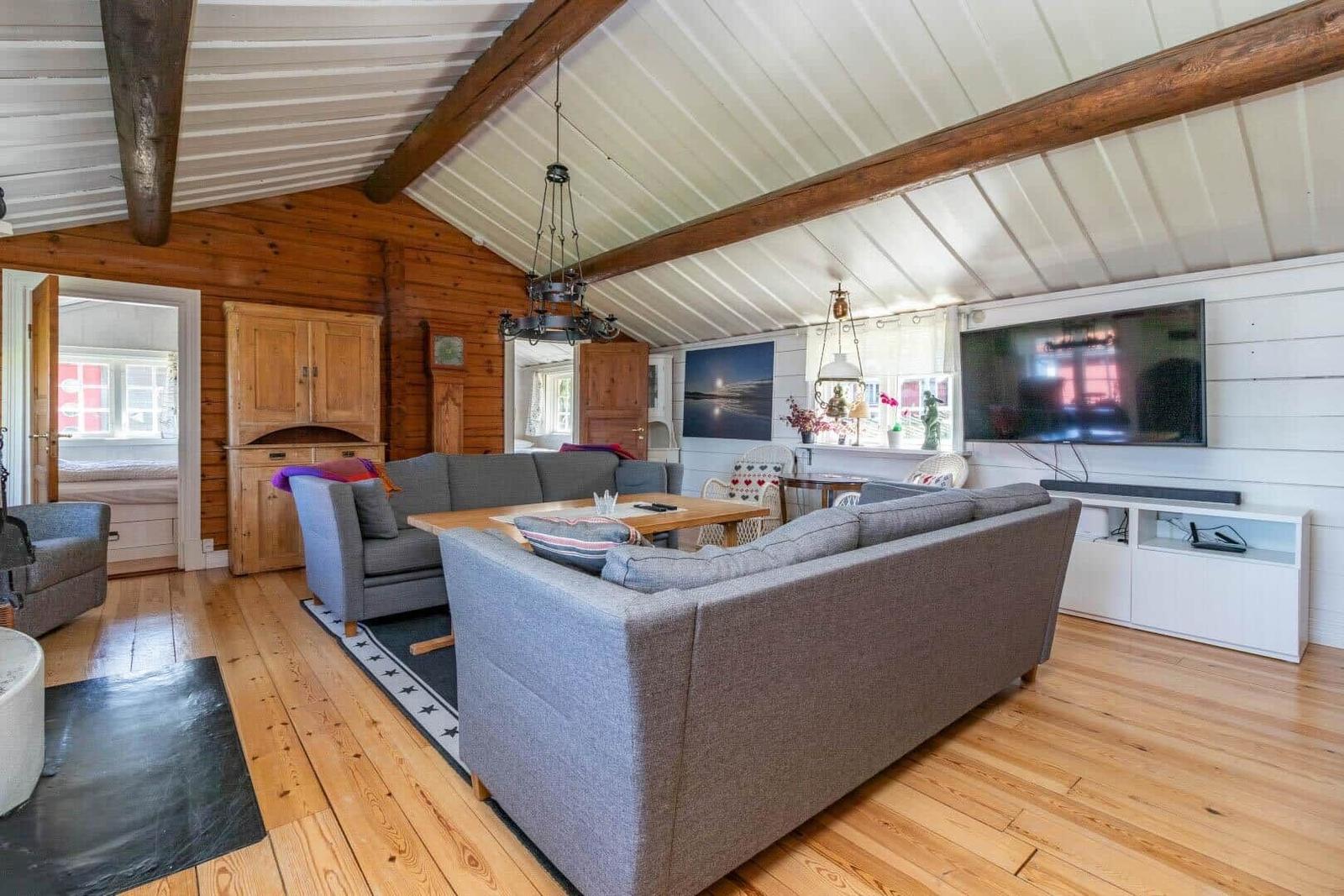 Wohnzimmer mit Holzboden, Sofa, Fernseher und Holzbalken an der Decke.