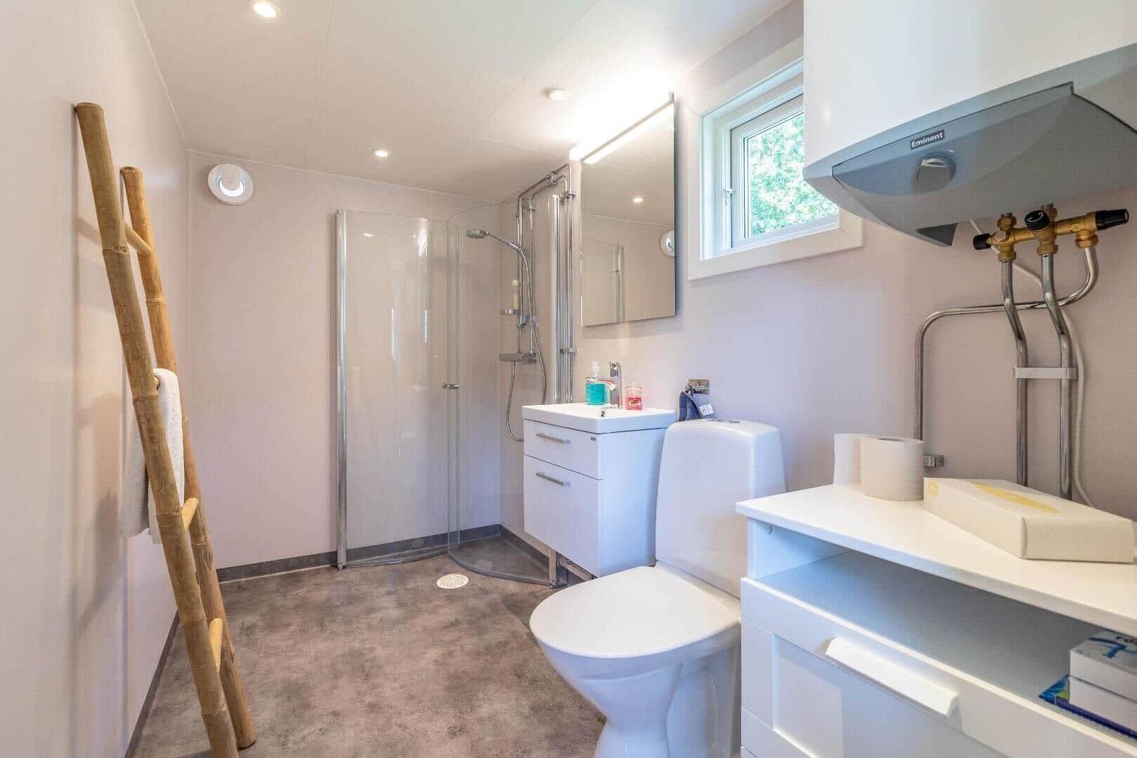 Badezimmer mit Dusche, Toilette und Waschbecken. Holzhandtuchhalter an der Wand.