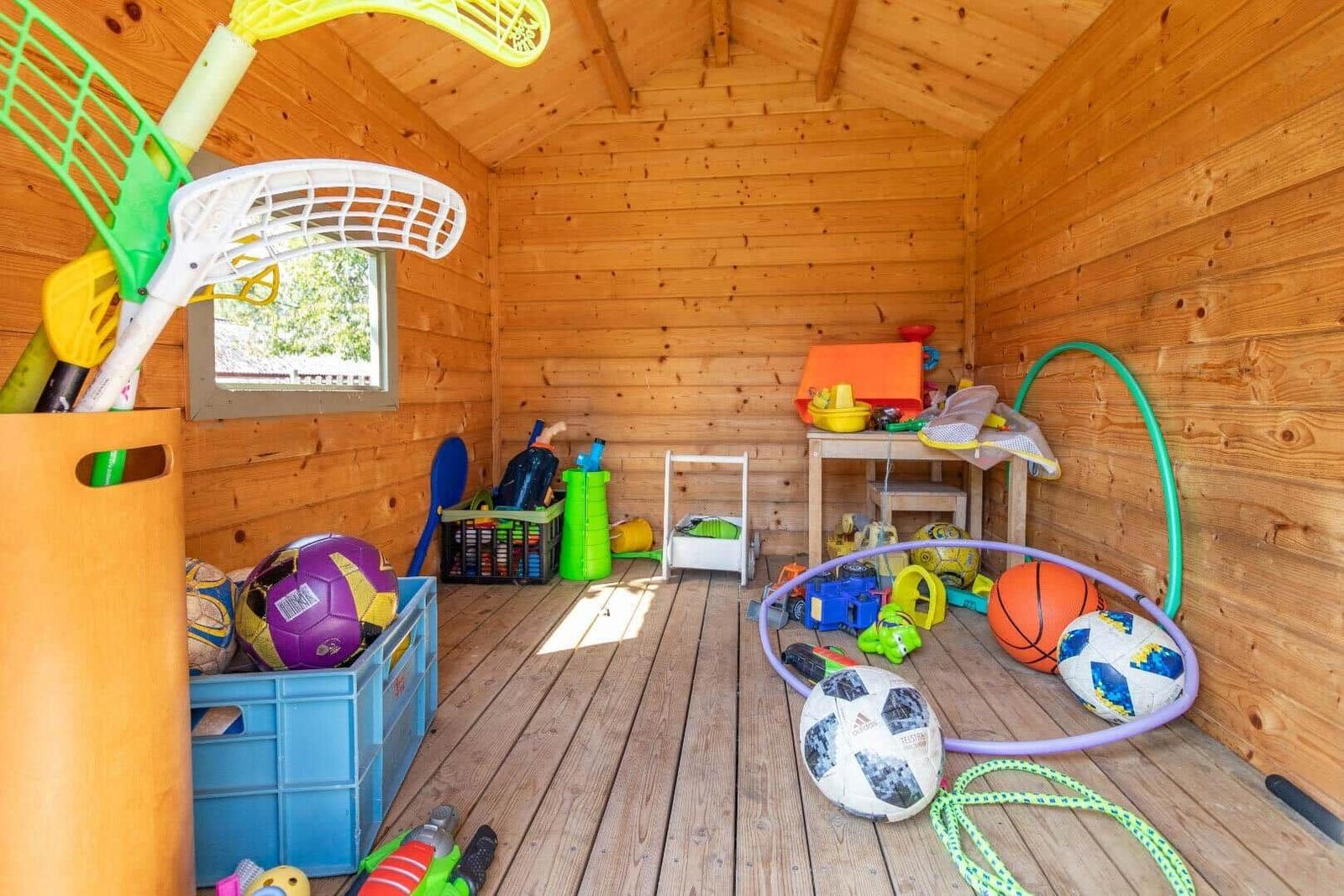 Holzvertäfelte Spielhütte mit bunten Spielzeugen und Kisten.