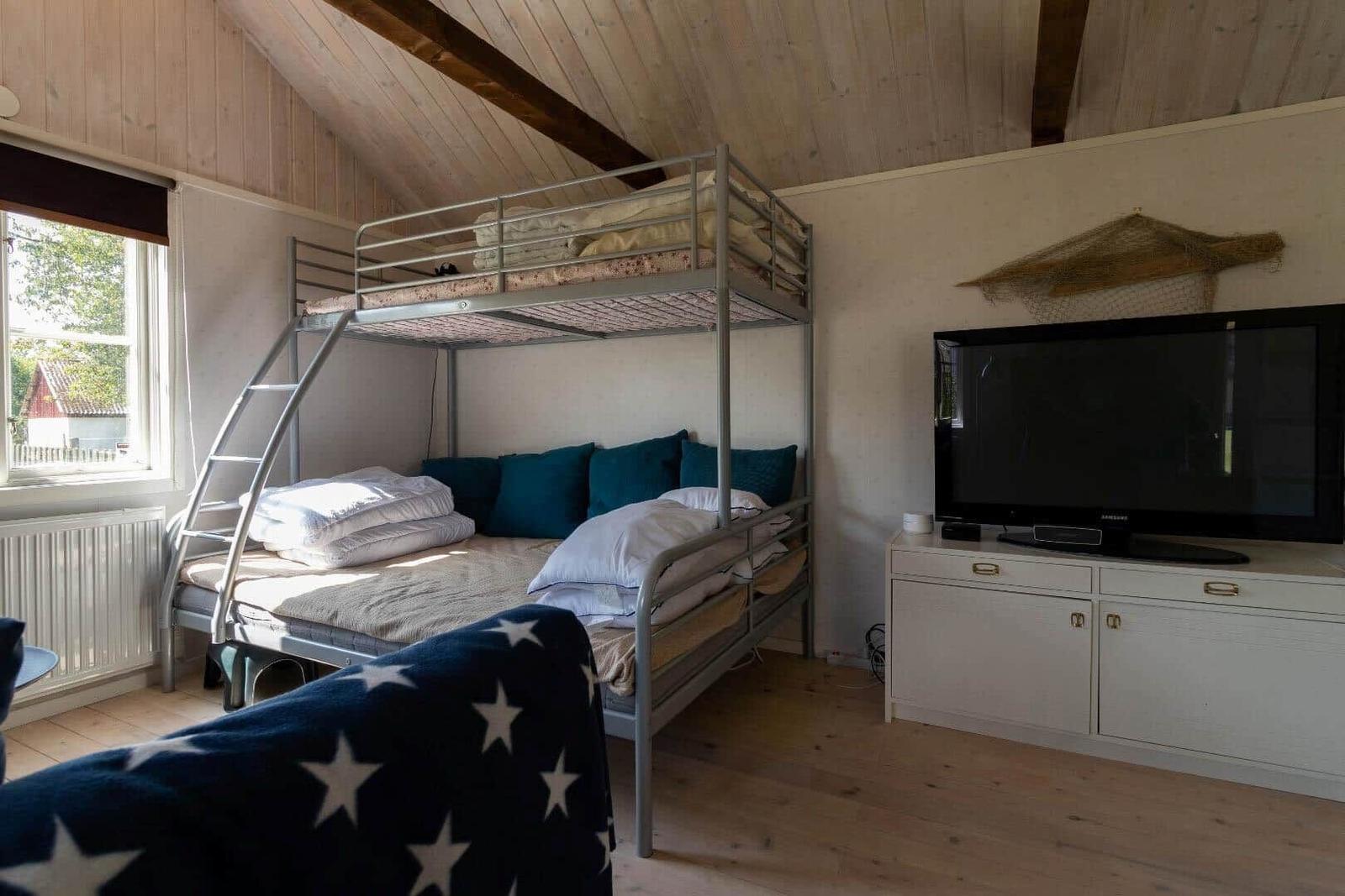 Zimmer mit Doppelstockbett, Fernseher und Fenster mit Blick nach draußen.
