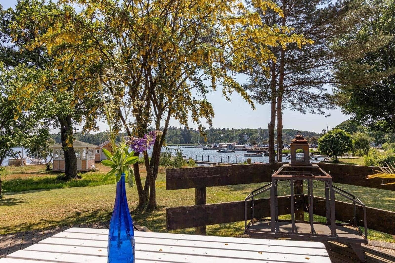 Terrasse mit Blick auf Hafen und Bäume. Blauer Vase mit Blumen.