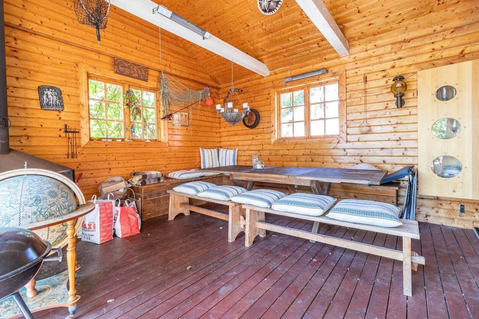 Holzvertäfelte Raum mit Tisch, Bänken und Kissen. Fenster, Deckenbalken und Globus sichtbar.