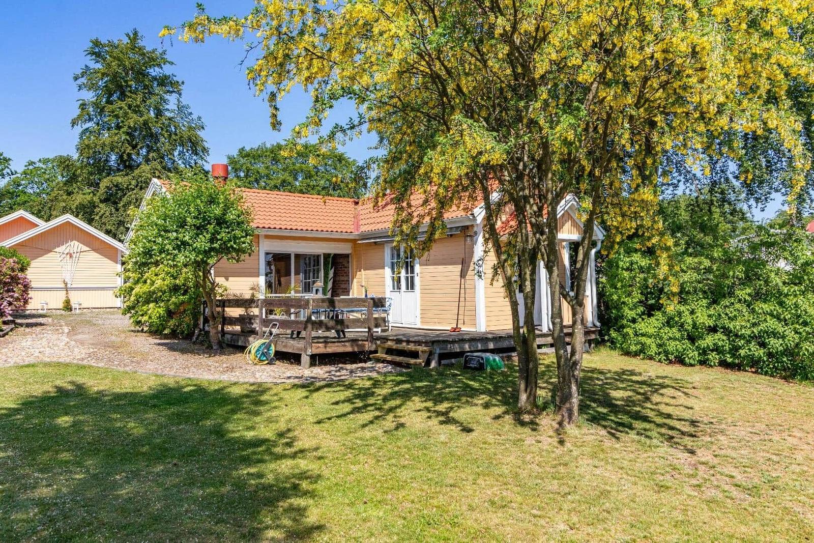 Ein gelbes Haus mit Terrasse und umliegenden Bäumen im Garten.