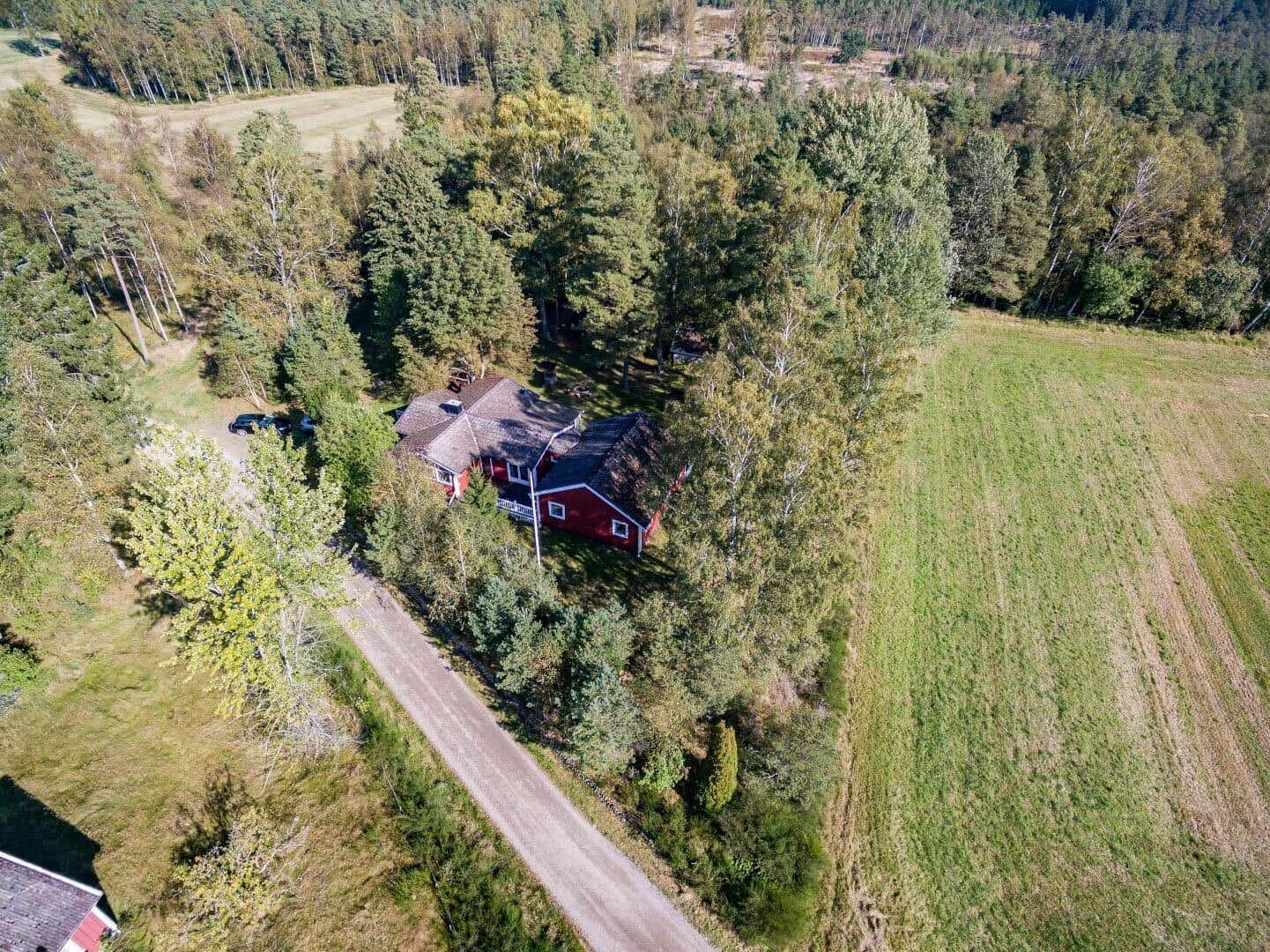 Rotes Haus in Wald und Feld, mit Waldweg und Parkplatz.