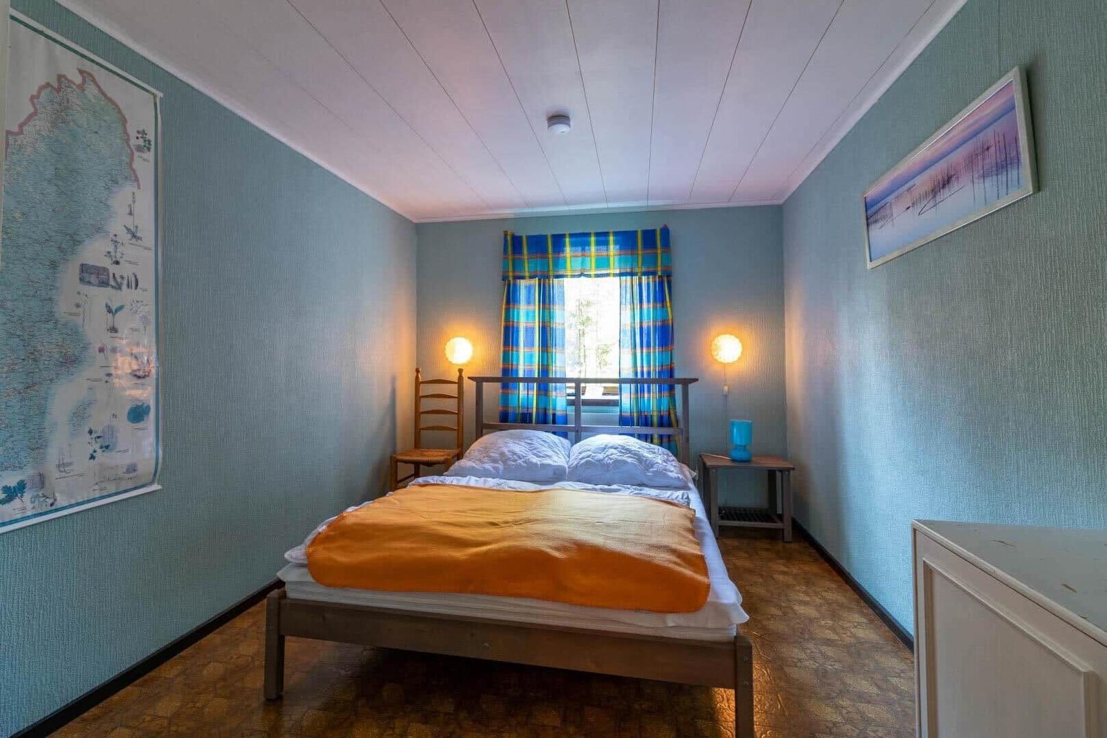 Schlafzimmer mit Bett, Fenster und Wandkarte.