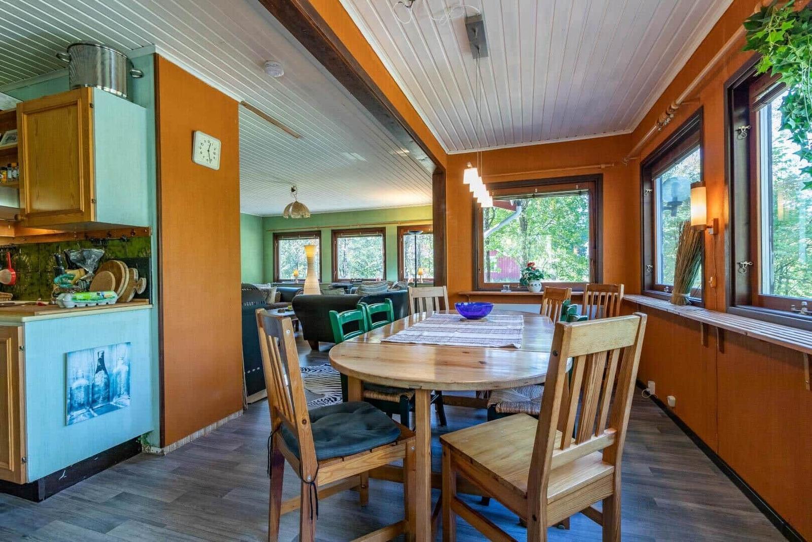 Essbereich mit Holztisch und Stühlen, Küche und Wohnzimmer im Hintergrund.