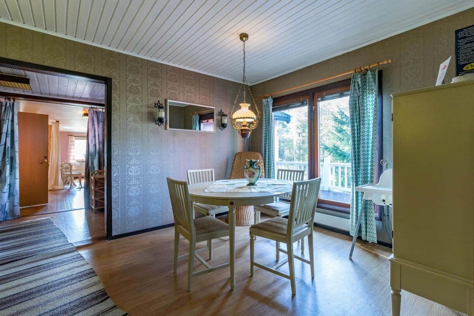 Esszimmer mit runden Tisch, Stühlen und Fensterblick auf Balkon