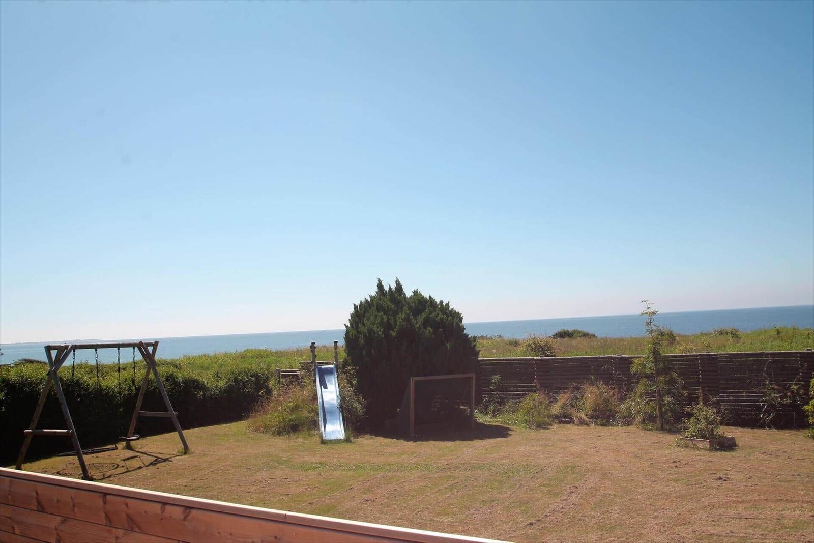Hinterhof mit Rutsche und Schaukel, Blick auf das Meer.