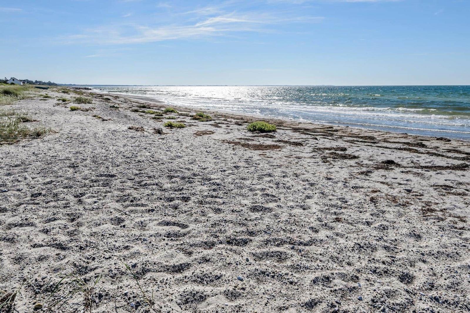 Strand mit feinem Sand und Wellen, das Meer ist klar und weit.