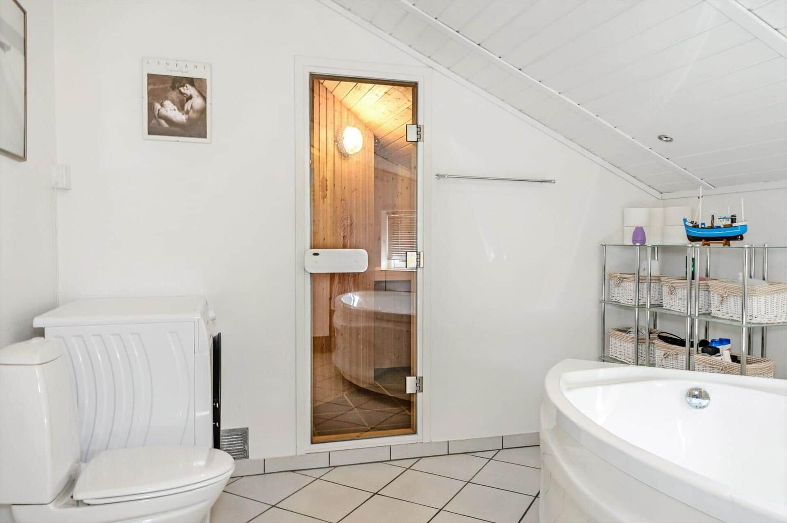Bathroom with shower, toilet, and bathtub. Sauna with wooden wall in background.