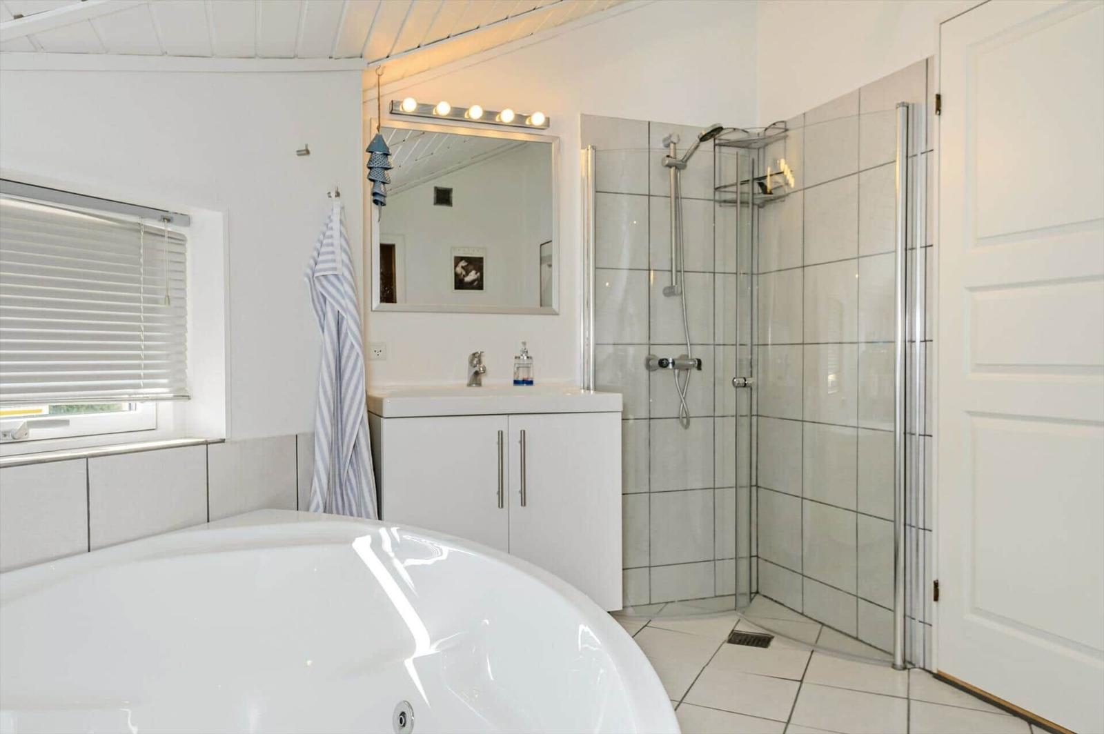 Bathroom with shower, sink and whirlpool tub. Window with blinds.