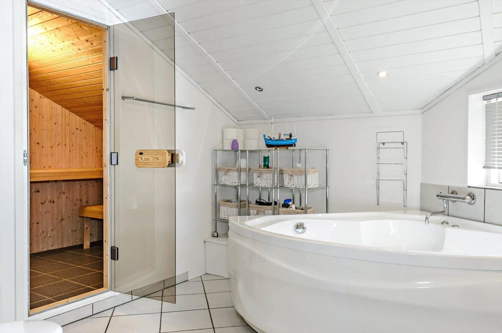Bath with whirlpool and adjacent sauna. Shelf with baskets and model boat.