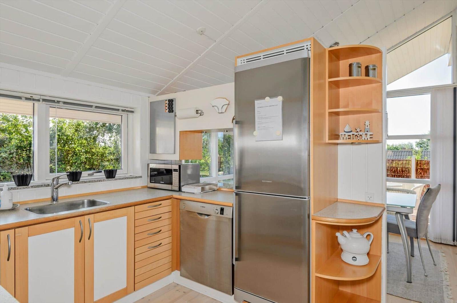 Kitchen with stainless steel appliances, wooden cabinets, and garden view.