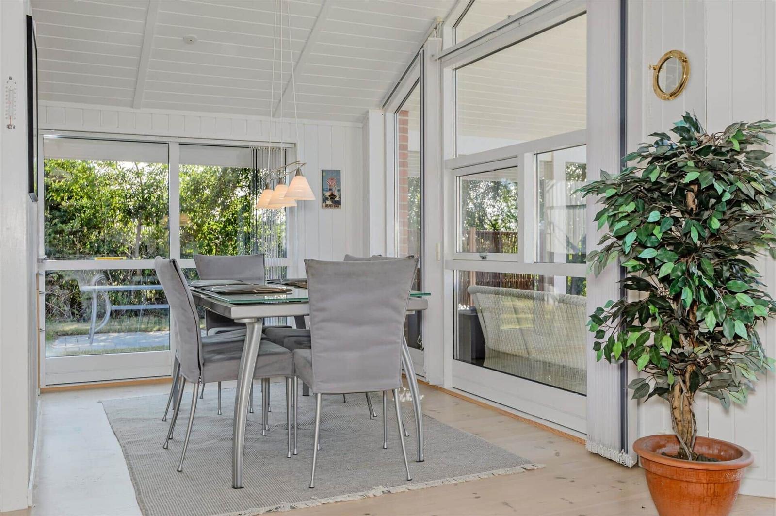 Dining room with glass top, gray chairs, and potted plant against wall.
