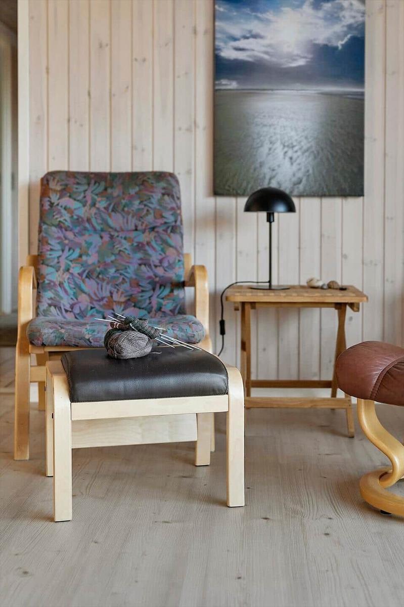 Ein Sessel mit Muster, ein Hocker und ein Tisch mit Lampe.