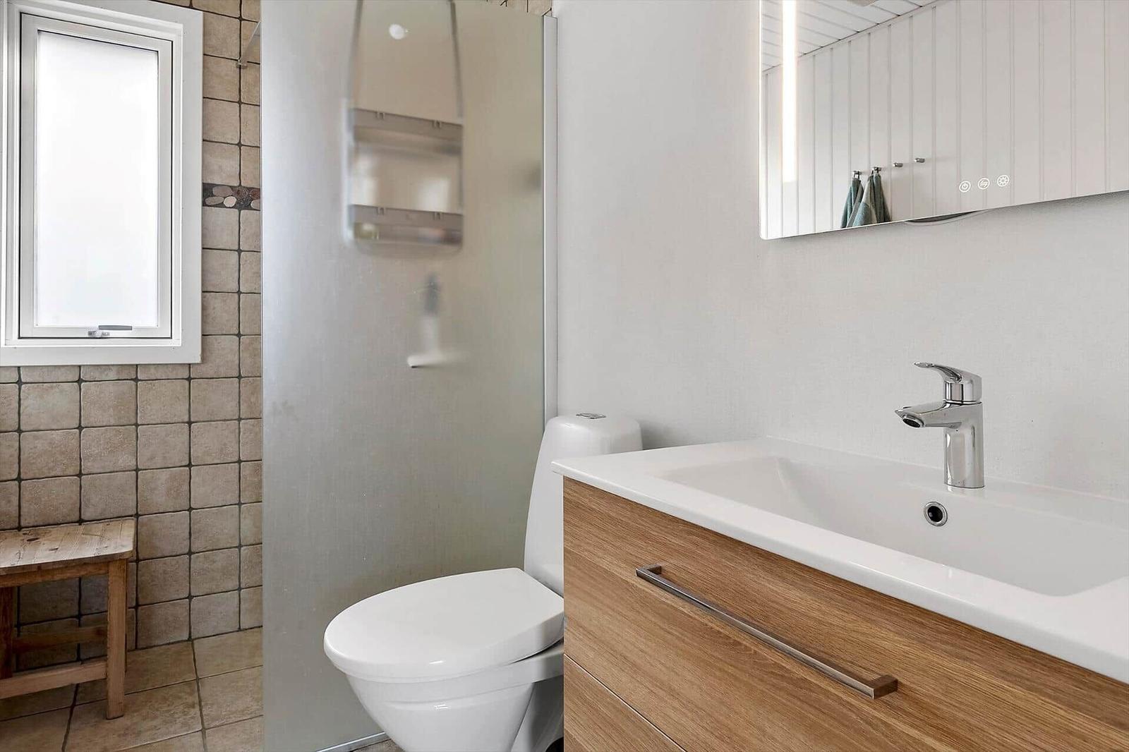 Badezimmer mit Dusche, Toilette und Waschbecken mit Spiegel.