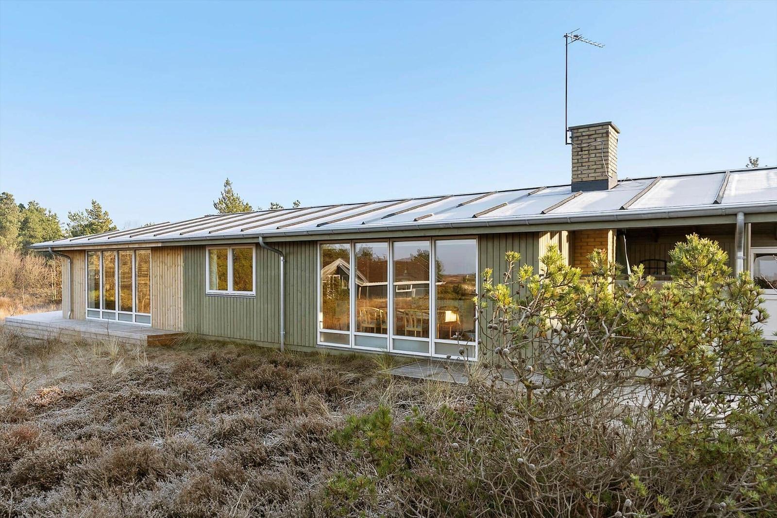 Moderne Strandhaus mit großem Fensterfront und Holzfassade im Freien.