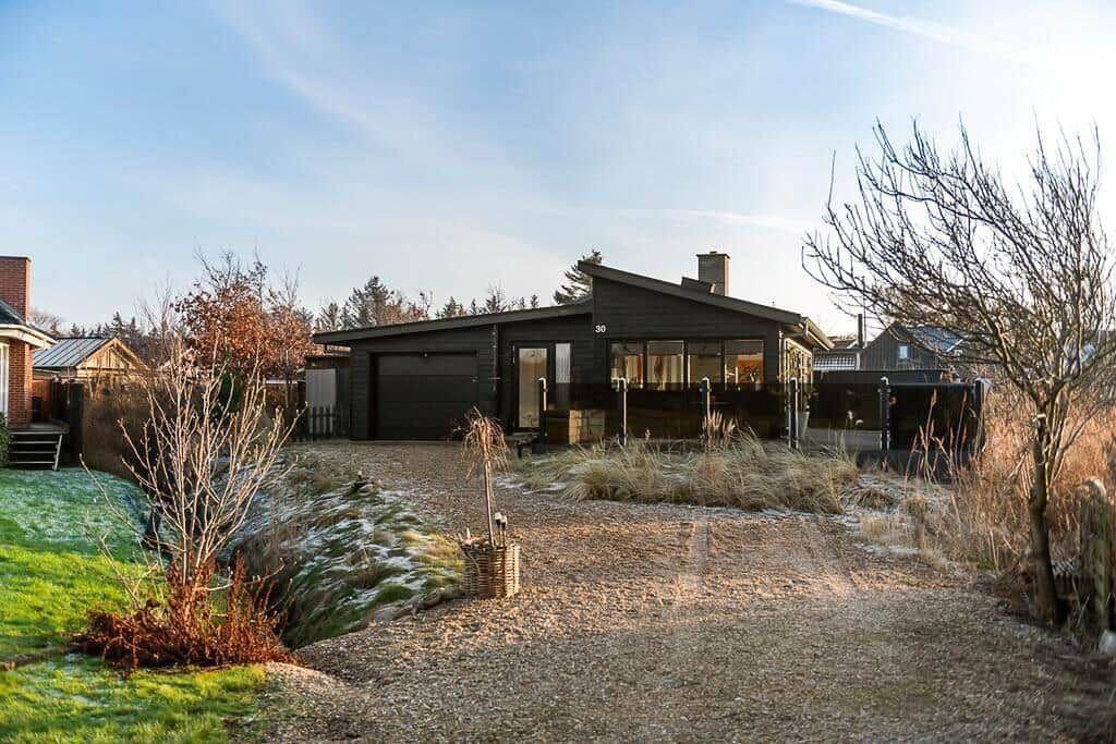 Moderne Villa mit Garage und Gartenweg. Holzverkleidung und großzügige Fenster.