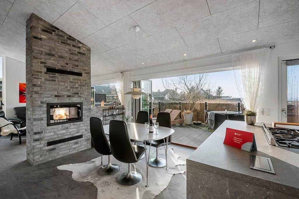 Moderne Küche mit Esstisch, Kamin und Blick auf Balkon.