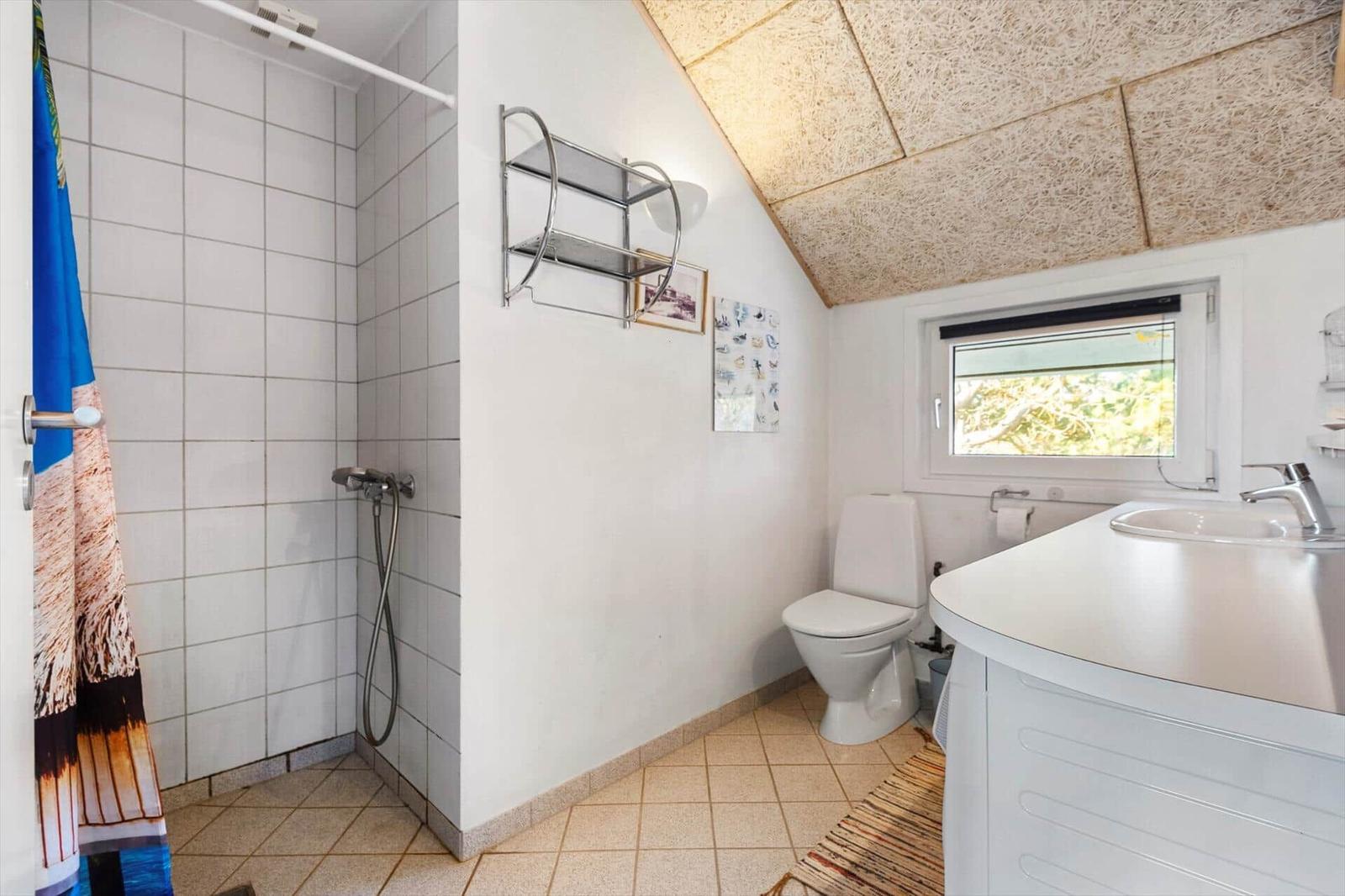Badezimmer mit Dusche, Toilette und Waschbecken unter schrägem Dach