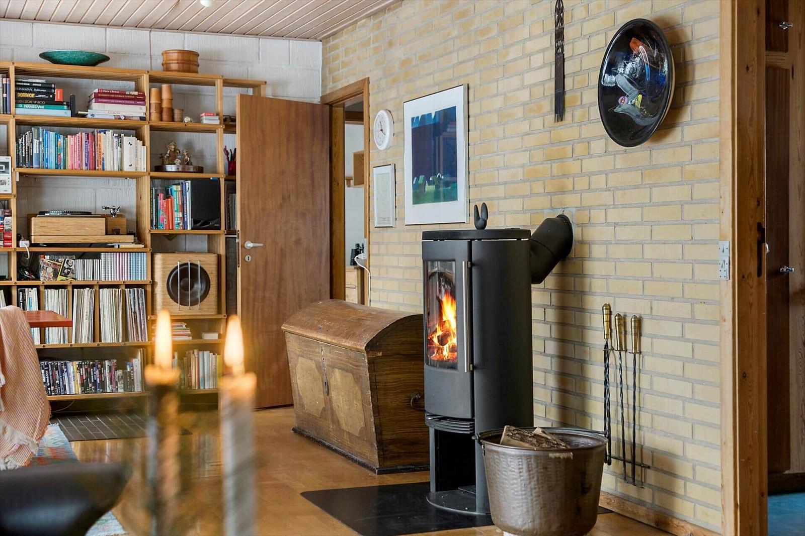 A room with a wood stove, bookcase, and hardwood floor. A picture hangs on the wall.