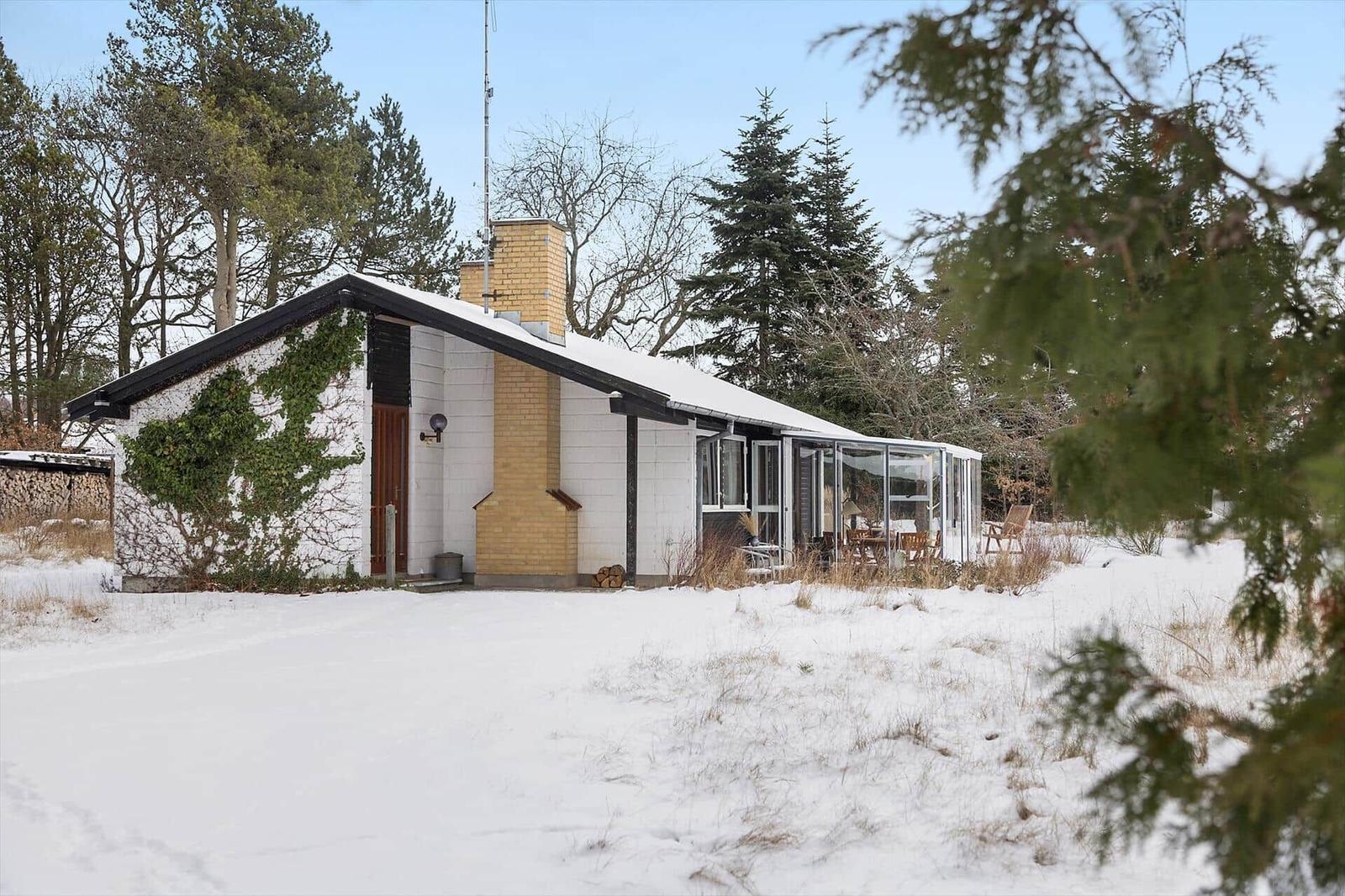 House with snow-covered roof and glass veranda in winter.