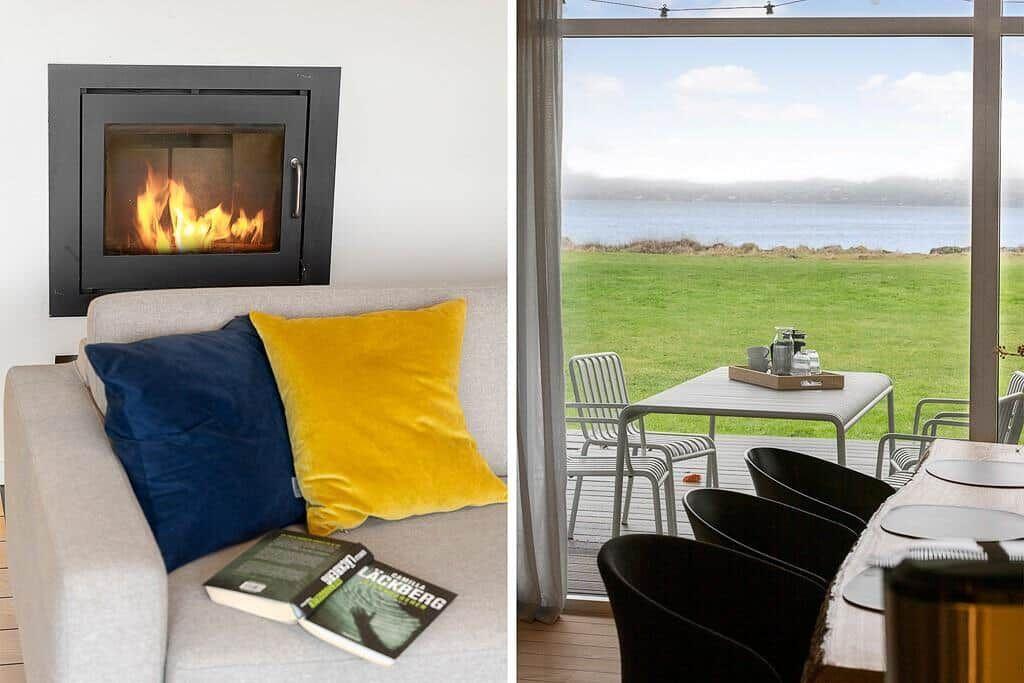 Fireplace with burning fire, sofa with cushions and book. Terrace with table, chairs and sea view.