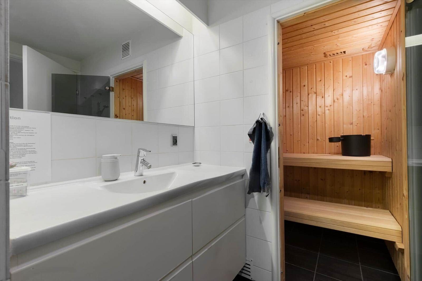 Bathroom with sink and integrated sauna with wooden bench and walls.